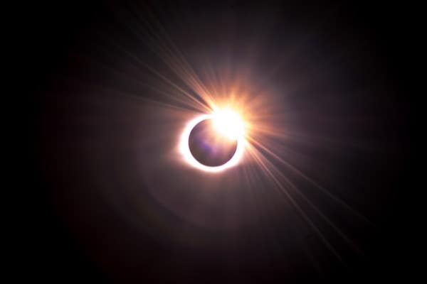 Solar eclipse photography setup with telephoto lens and tripod pointed at the sky