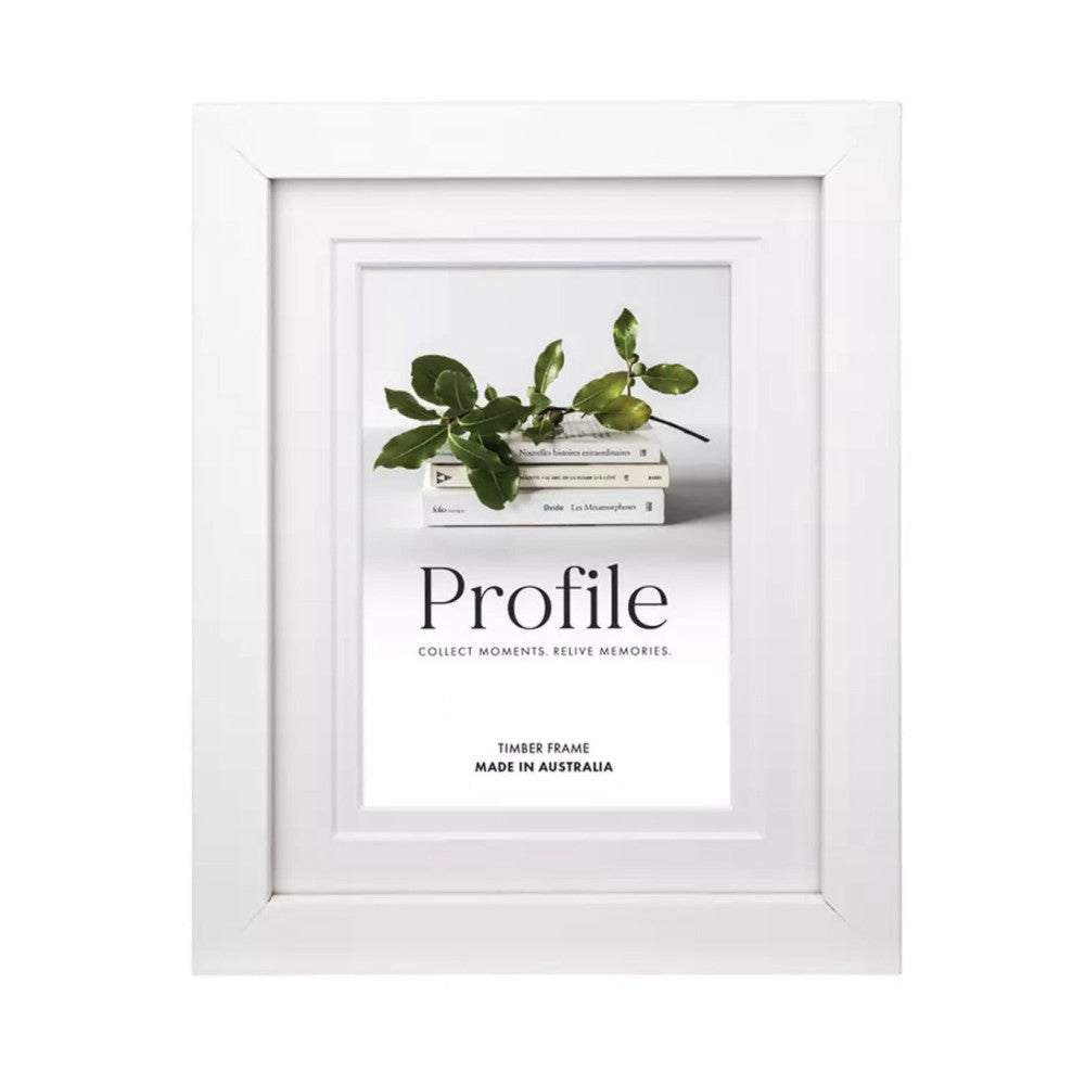 White timber frame displayed front-on, showing matted print with stacked books and green plant branch inside, tagline "Collect Moments. Relive Memories.