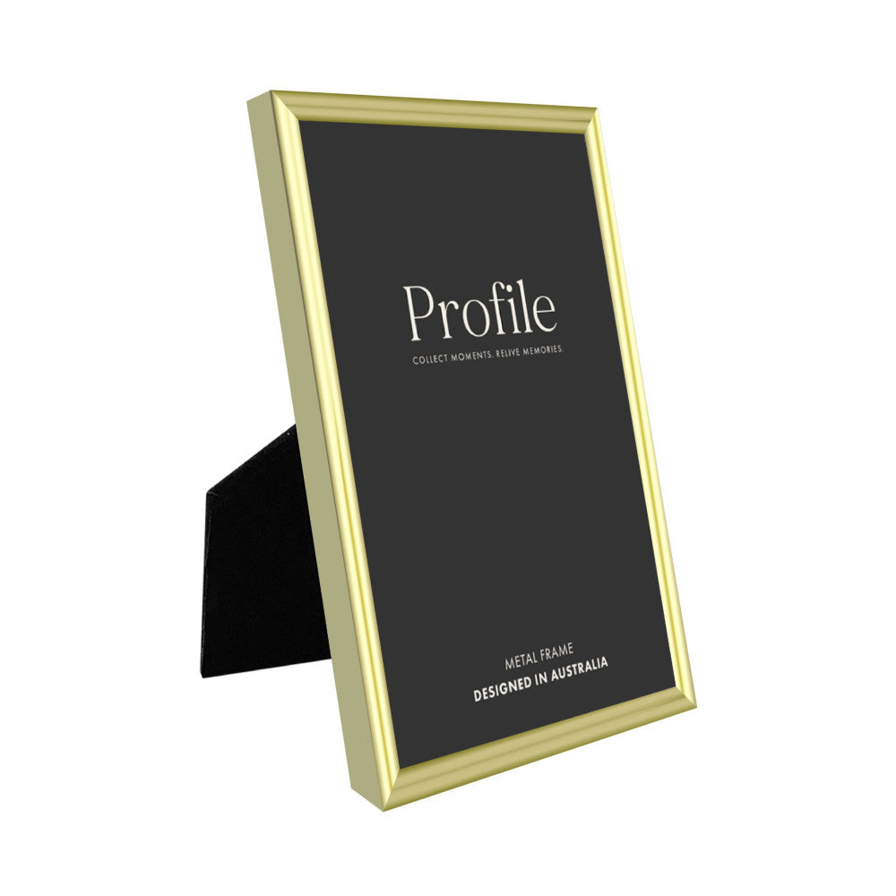 Gold metal photo frame displayed at an angle showing the front face with black interior mat and a black easel stand visible on the left side.