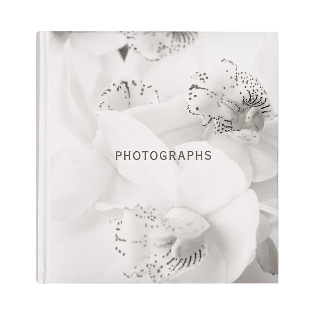 Front cover of white photo album featuring black and white orchid flowers with spotted petals and the word "PHOTOGRAPHS" centered on the spine.