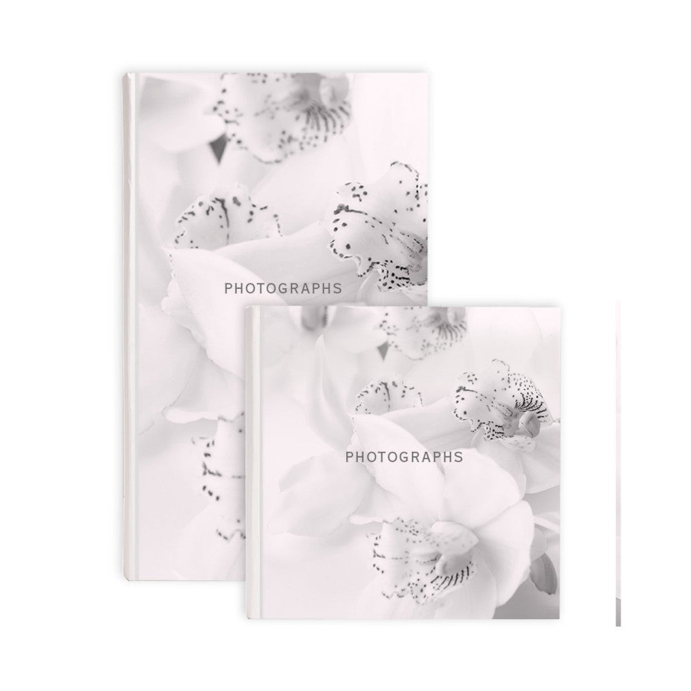 Two white photo albums displayed at angles showing orchid flower cover designs with "PHOTOGRAPHS" text overlay in soft focus black and white imagery.