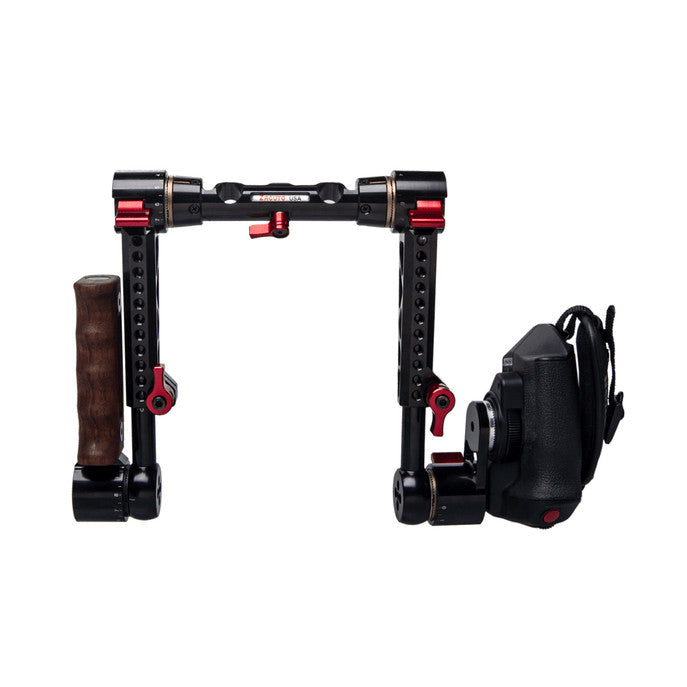Front view of black camera rig with red accents, dual wooden grip handles on sides, and shoulder pad attachment on right.