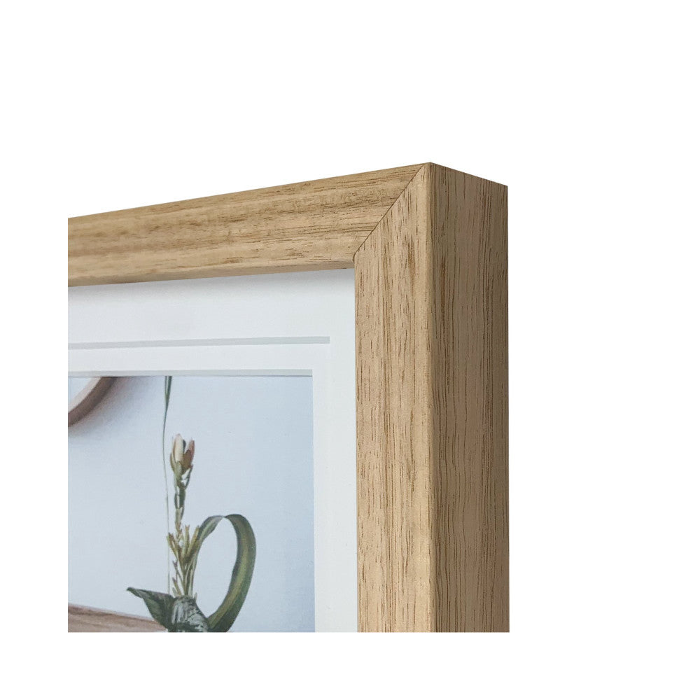 Close-up detail of light wood frame corner showing grain texture and beveled edge with matted opening.
