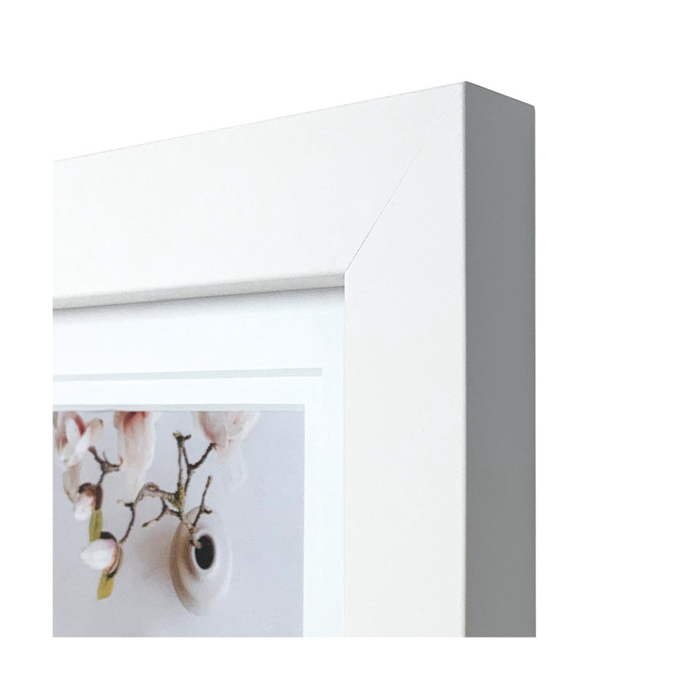 Close-up side profile view of white timber picture frame showing beveled edge detail and corner construction with floral artwork visible inside.