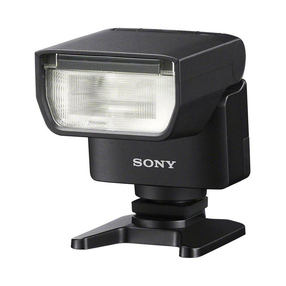 Black Sony flash unit shown at three-quarter angle with rectangular flash head, mounting foot, and stand base visible against white background.