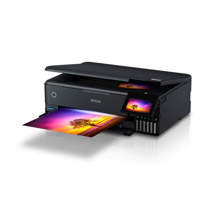 Black Epson EcoTank printer shown at an angle with colorful sunset photo printing from the open tray and displayed on the built-in screen.