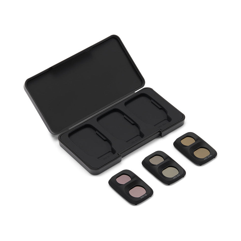 Open black case displaying three small square ND filters with tan and pink-tinted glass beside it, shown at an angle.