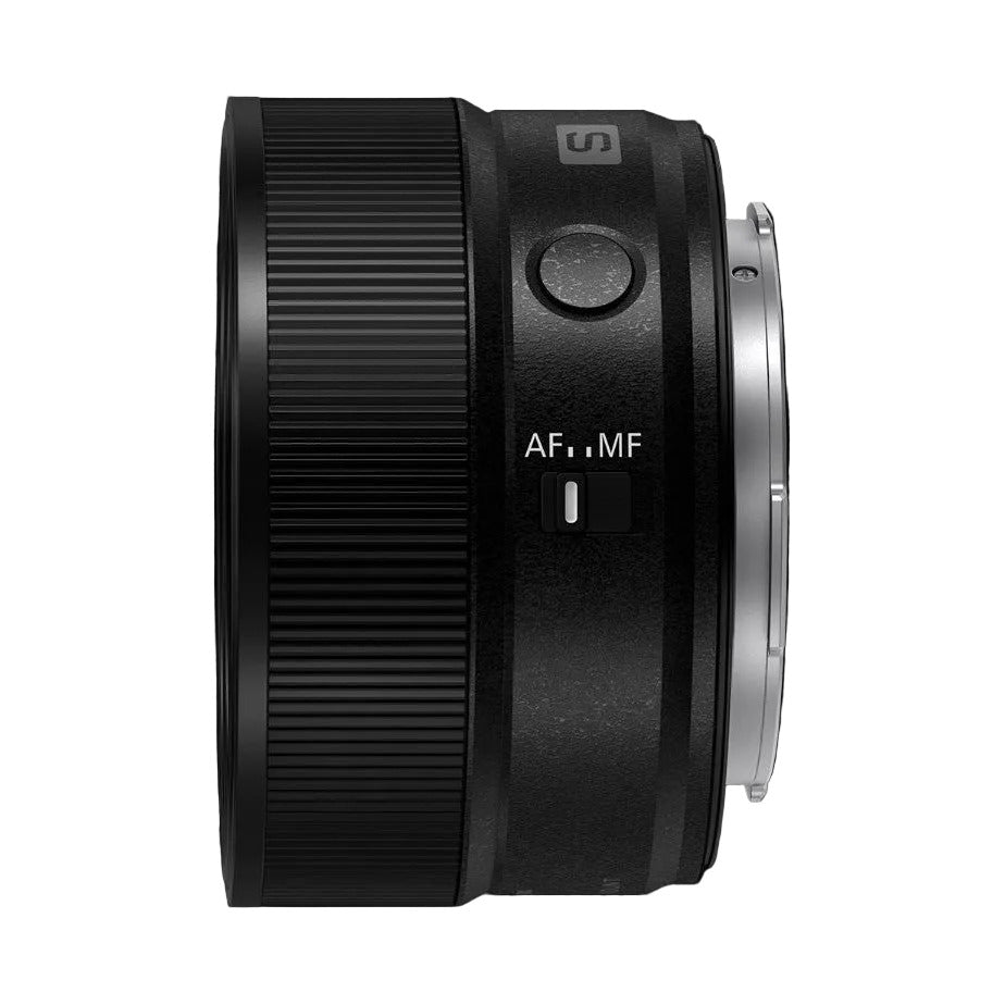 Side view of black Panasonic Lumix S 20mm F2.5 lens showing ribbed focus ring, AF/MF switch, and mount against dark background.