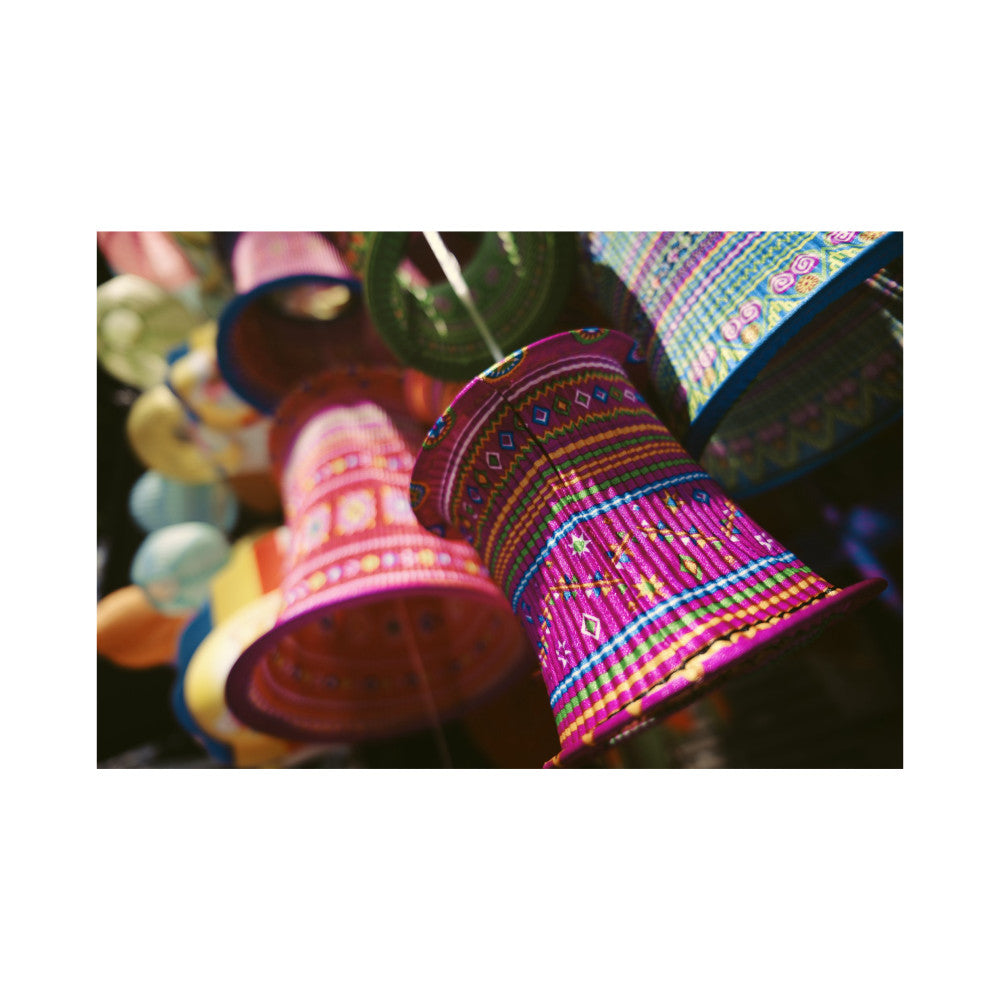 Colorful woven cylindrical decorative objects with geometric patterns in magenta, yellow, and blue, photographed in close-up detail.