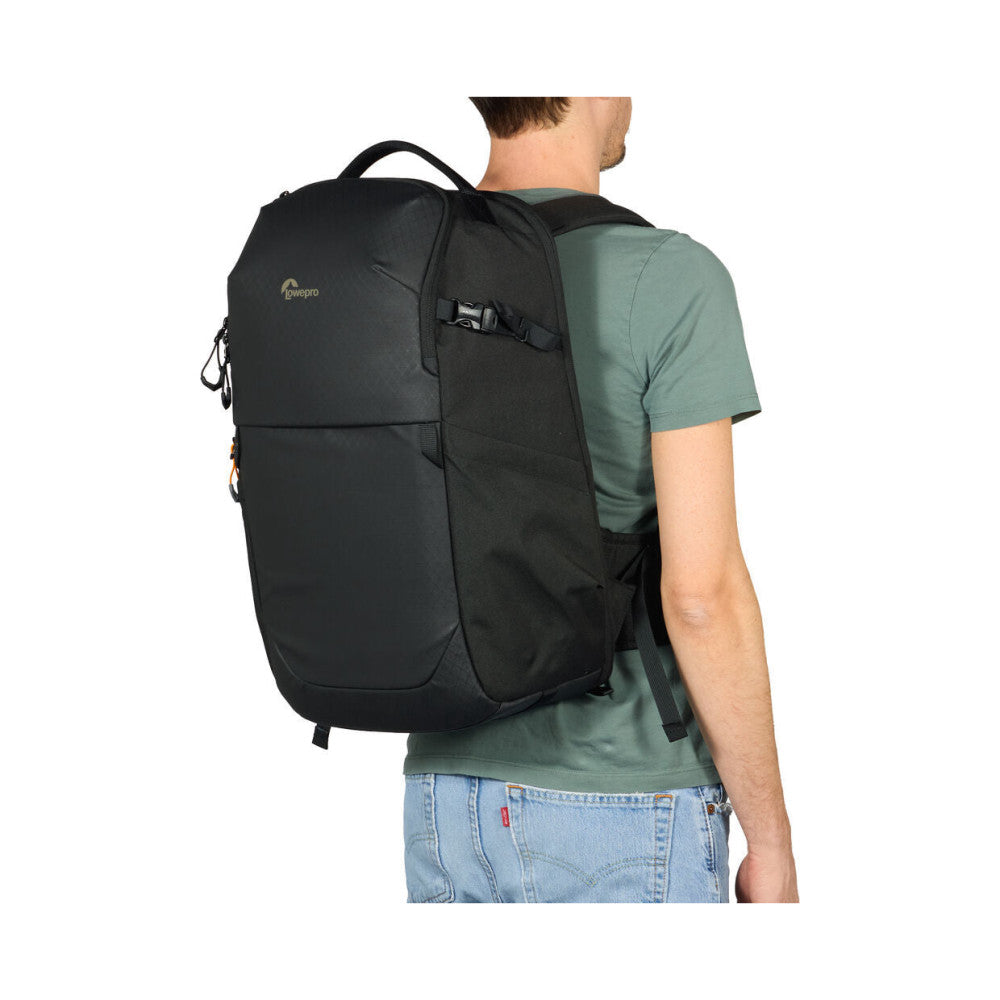 Man wearing black LowePro camera backpack from rear view, showing back panel design and shoulder straps against white background.