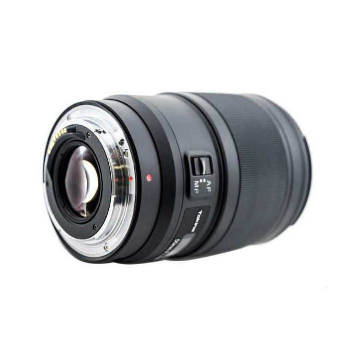 Side view of a black Tokina 50mm lens with chrome rear mount and focus ring against white background.