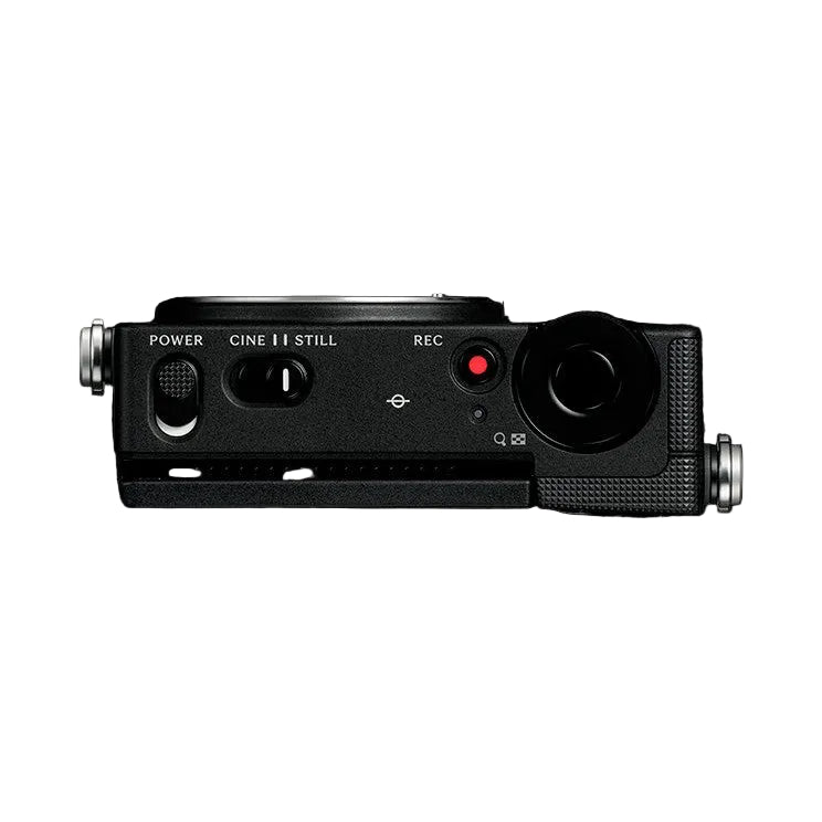 Top-down view of a black compact mirrorless camera with lens attachments, showing power switch, mode dial, and red recording indicator light against a dark background.