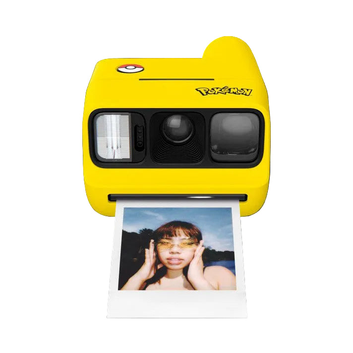 Yellow Polaroid GO camera with Pikachu design shown from front angle, ejecting an instant photo of a person wearing yellow sunglasses against a black background.