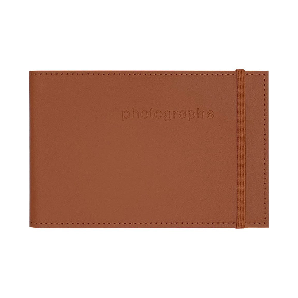 Cinnamon brown leather photo album with embossed "photographs" text, elastic band closure, and stitched edges, shown flat from front view.