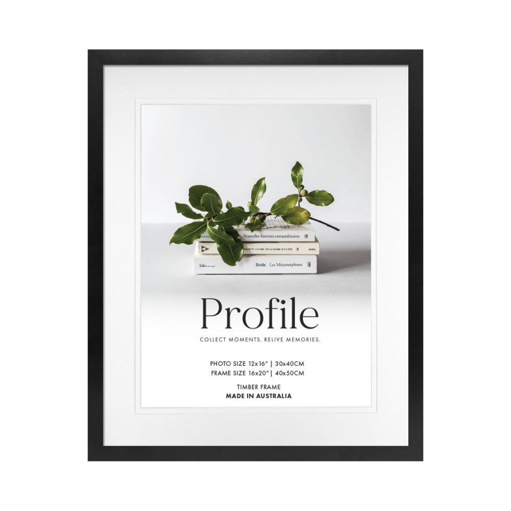 Black timber picture frame displayed front-facing with white matting, showing a styled photograph of green plant branches on stacked books.
