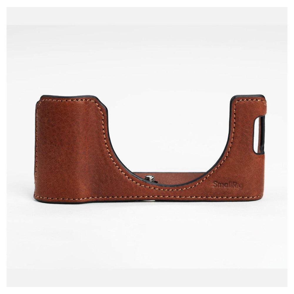 Brown leather camera half case with curved cutout design and contrasting stitching, shown from side view against white background.