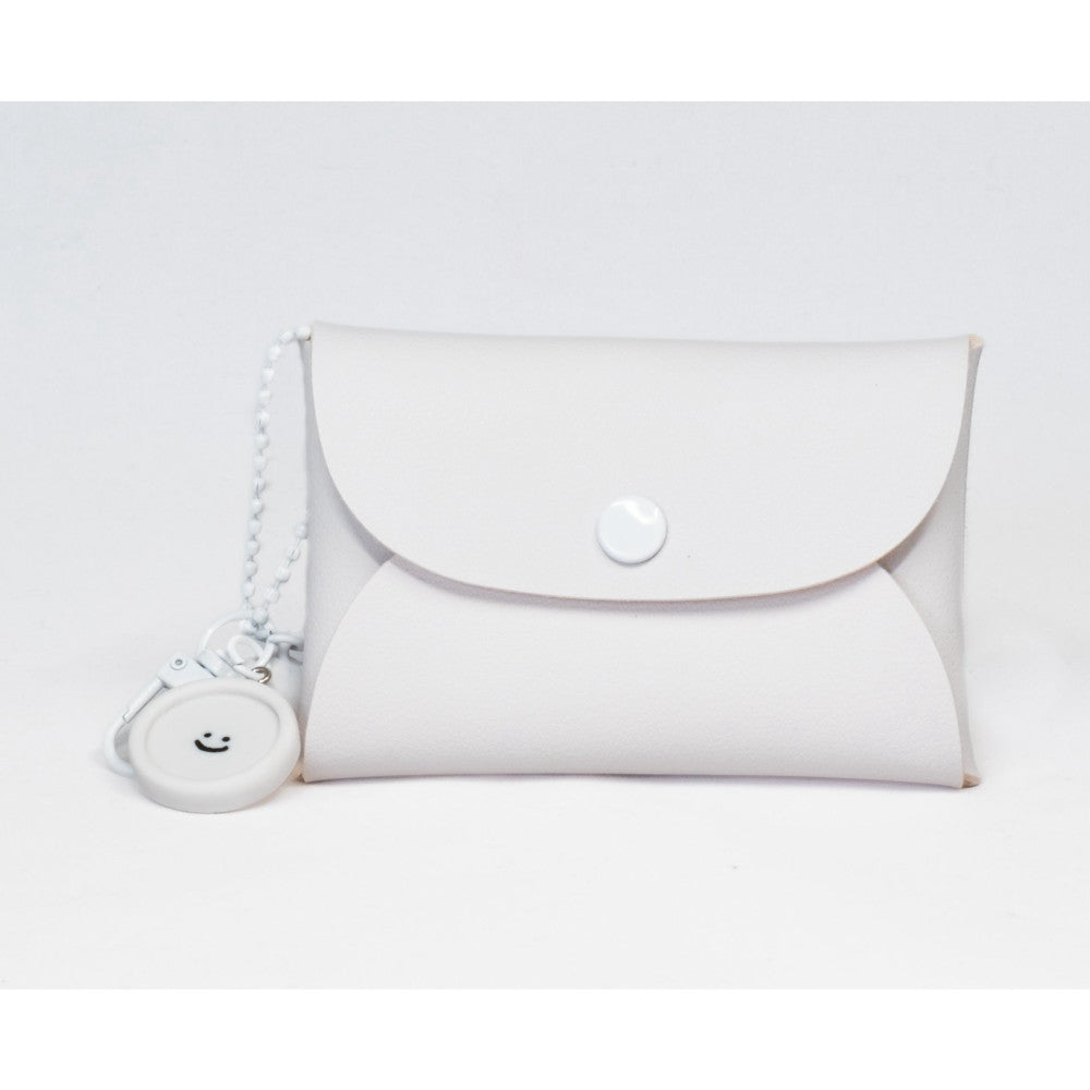 White clutch bag with snap closure and matching circular keychain with smiley face, displayed against plain white background.