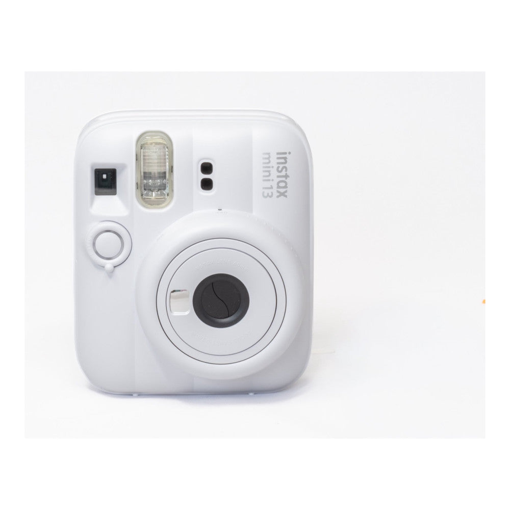 White Fujifilm Instax Mini 13 instant camera shown from front, displaying lens, flash, shutter button, and viewfinder against plain background.