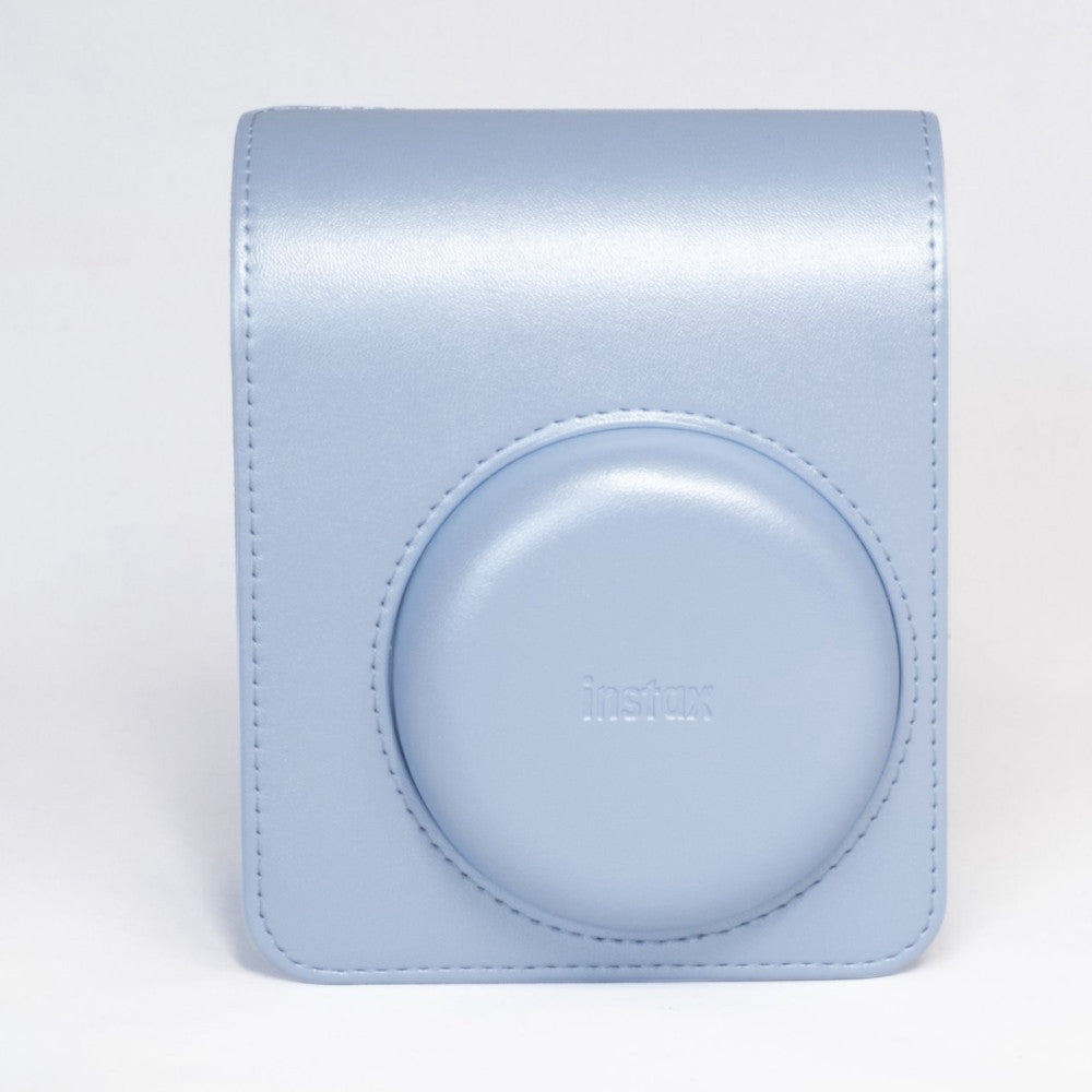 Light blue Instax Mini carrying case with circular lens opening and "instax" branding, shown against white background.
