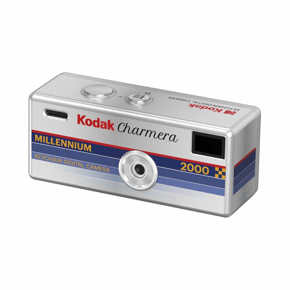 Silver rectangular keychain digital camera shown from angled front view, displaying lens, two buttons, and Kodak Charmera Millennium 2000 branding with red and blue stripes.