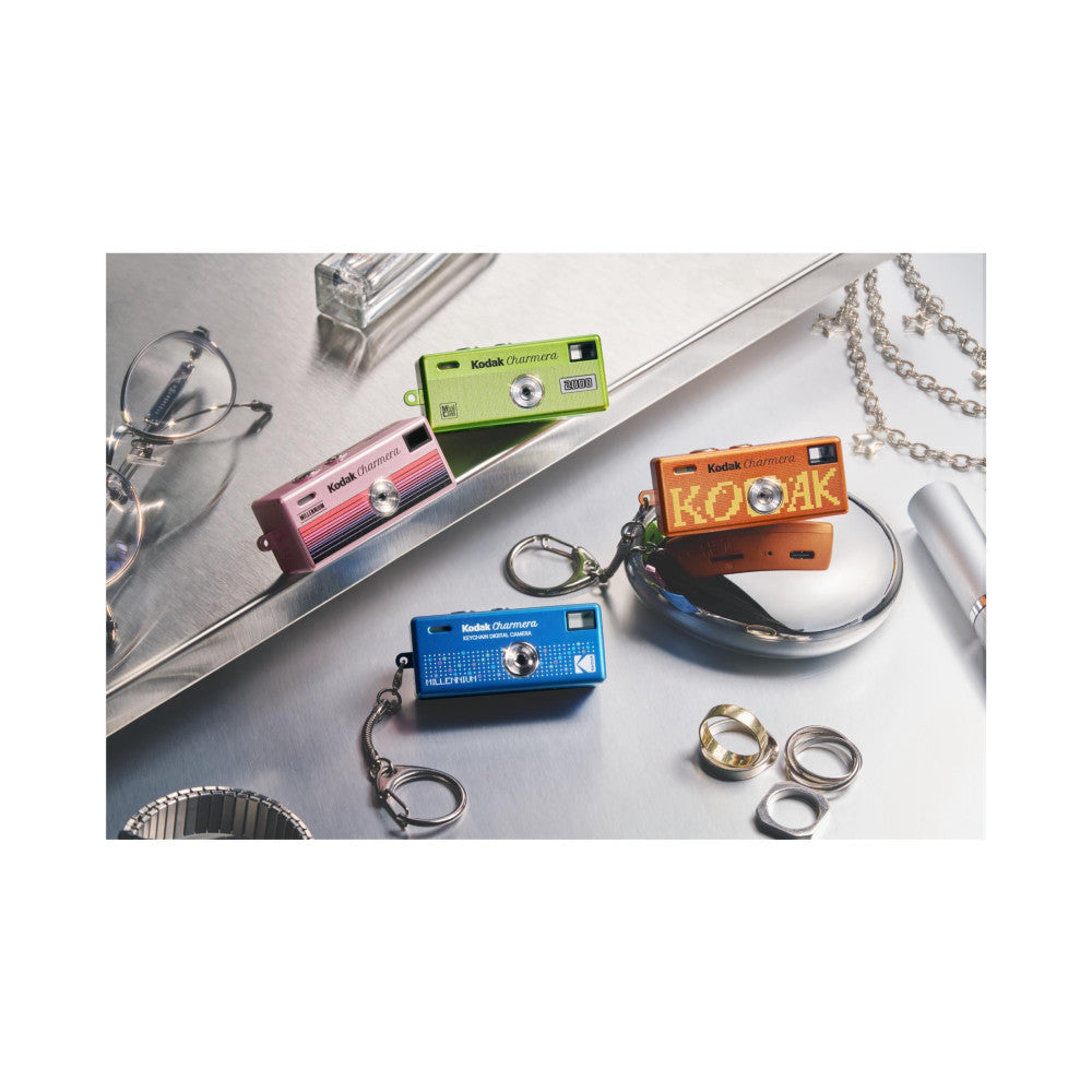 Colorful Kodak Charmera miniature digital cameras with keychains displayed on white surface with accessories and jewelry.