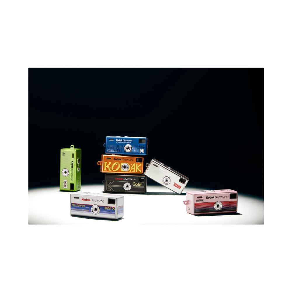 Collection of Kodak Charmera keychain cameras in various colors displayed against black background, showing multiple models and color options.