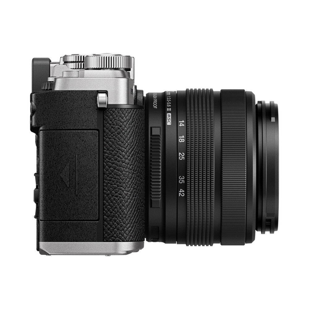 Side view of silver OM System PEN camera with black leather grip and attached black 14-42mm zoom lens against white background.