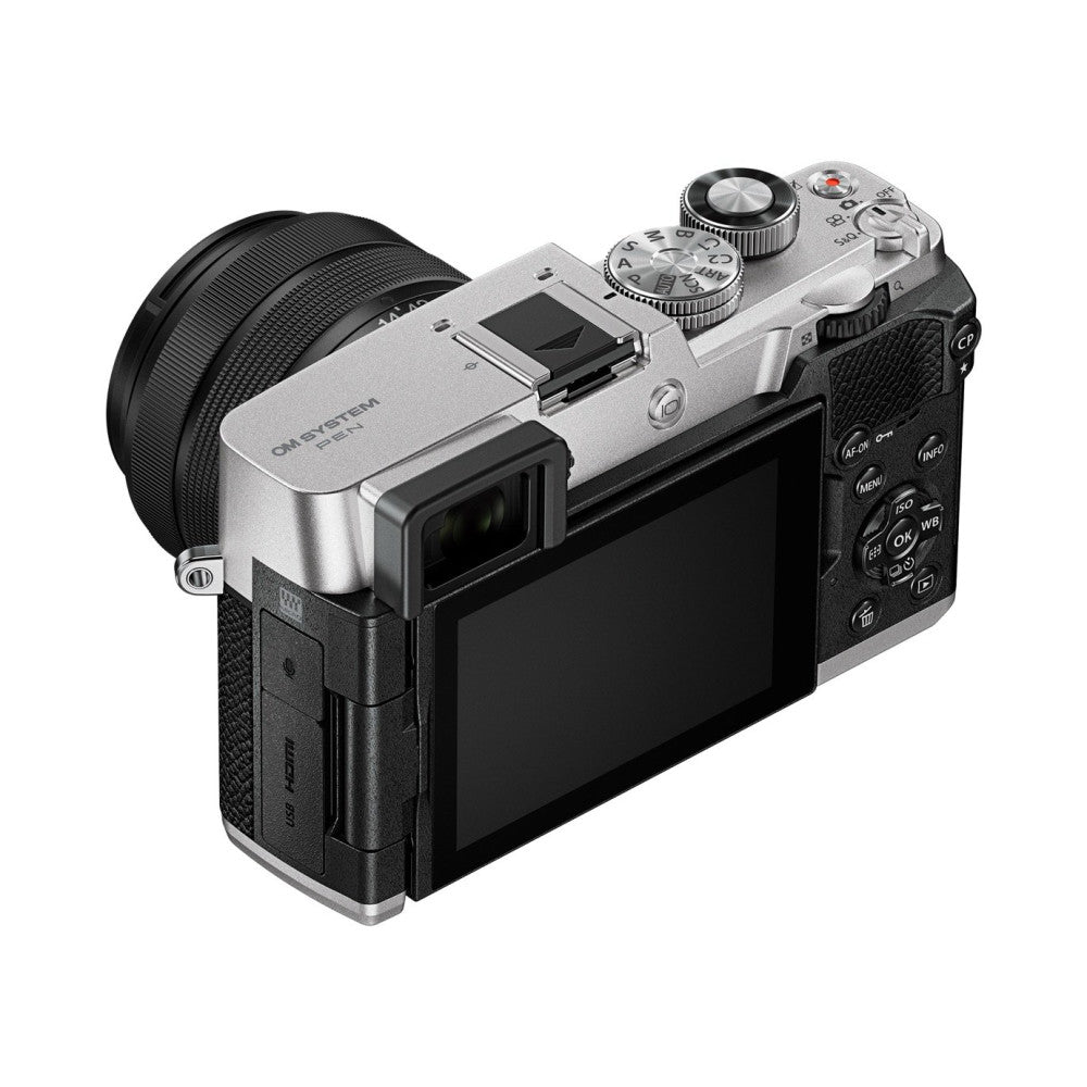 Three-quarter rear view of silver and black OM System PEN mirrorless camera with attached black 14-42mm lens and LCD screen visible.
