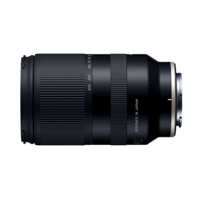 Black telephoto zoom lens shown from the side, displaying focal length markings and "Designed in Japan" text on the barrel.