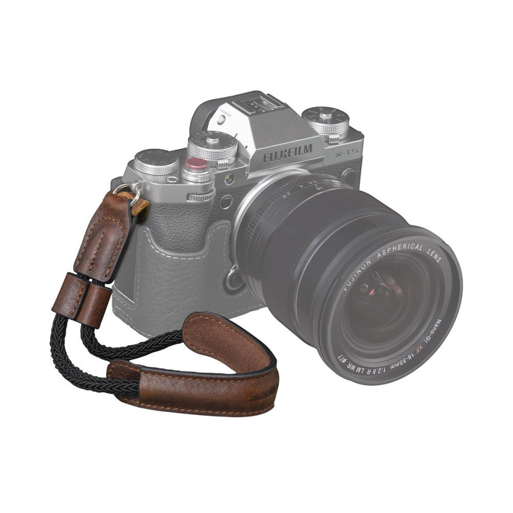 Brown leather and black woven camera wrist strap attached to Fujifilm X-T5 camera, shown at three-quarter angle against white background.