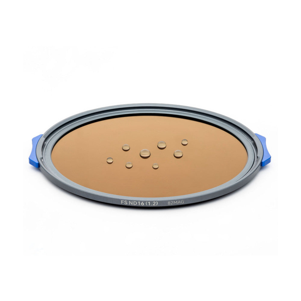 Angled top view of a circular filter with gray frame, blue handles, and tan-colored glass showing water droplets, labeled FS ND16 (1.2) 82MAG.