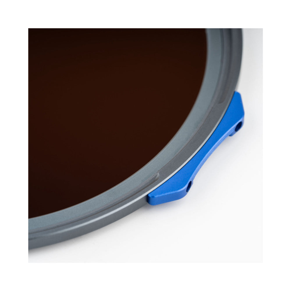 Close-up detail of magnetic filter ring attachment with blue lever clip on gray metal rim against white background.