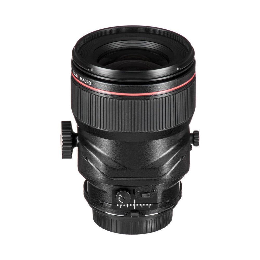 Black Canon tilt-shift macro lens displayed front-facing, showing red band, focus ring, and shift controls on barrel.