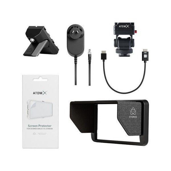 Atomos Creator Kit components laid out flat: monitor stand, power adapter, cables, screen protector packaging, and monitor hood with mounting bracket.