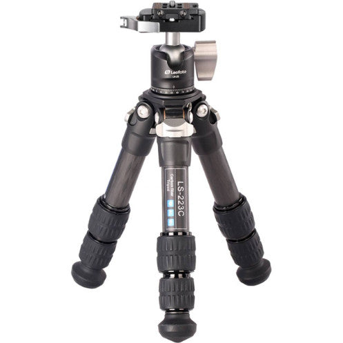 Black carbon fiber tripod with ball head and camera plate, shown fully extended in front view against white background.
