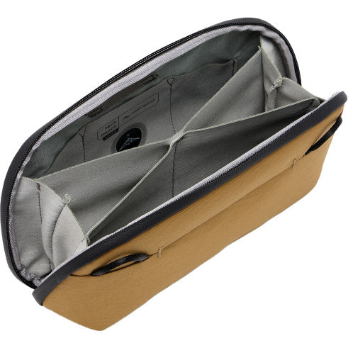Open tan and gray tech pouch viewed from above at an angle, showing interior dividers and cable management features.