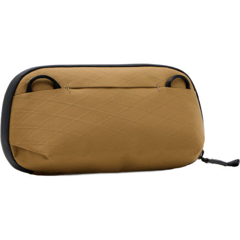 Top-down view of a tan quilted tech pouch with black trim and handles against a white background.