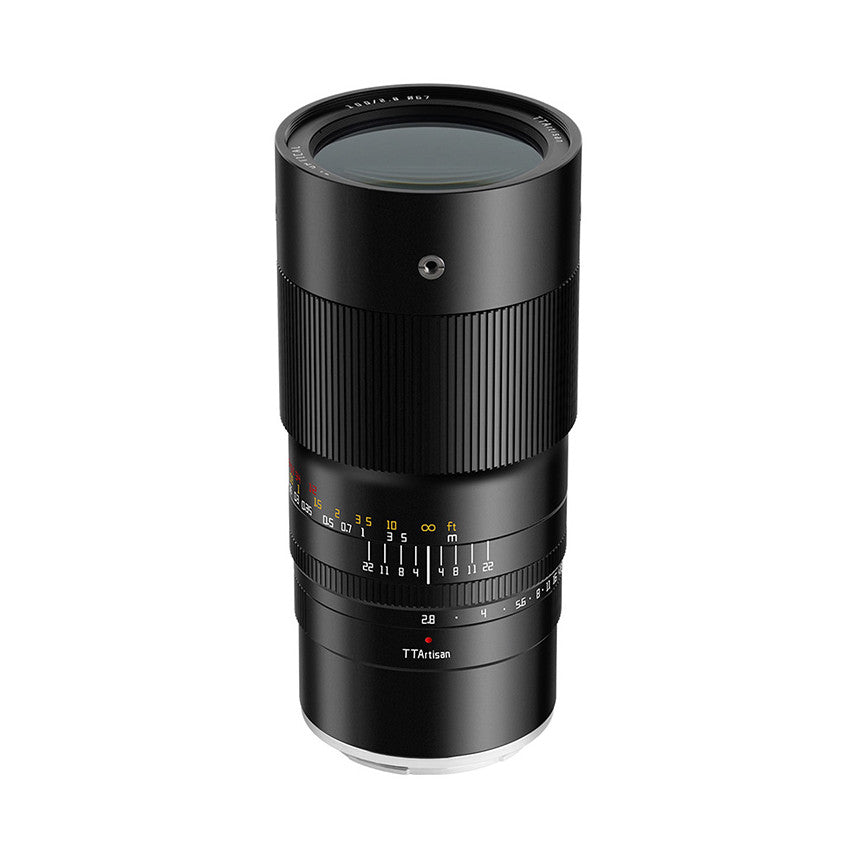 Black manual focus macro lens displayed at three-quarter angle showing front element, focus ring with distance markings, and TTArtisan branding on barrel.