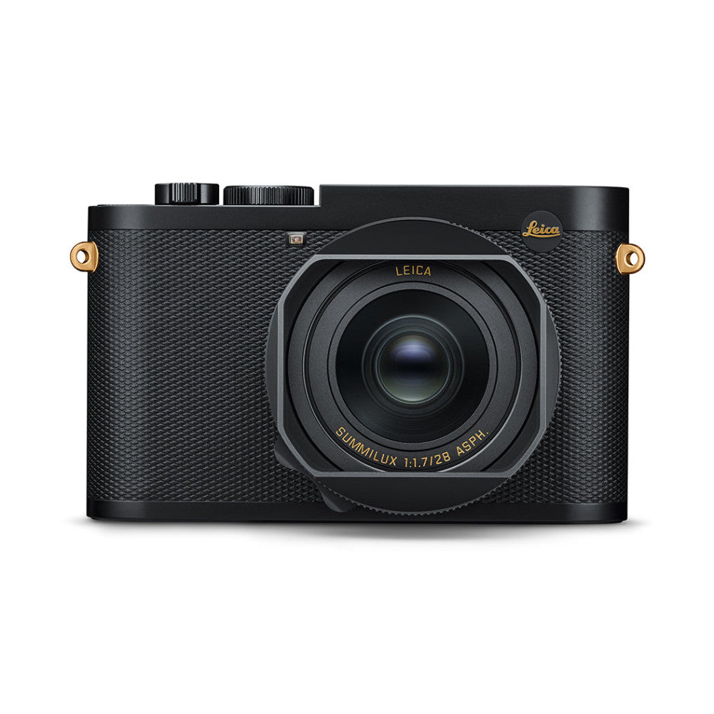 Black Leica Q2 compact camera viewed from front, showing fixed Summilux lens with gold accents and textured grip.