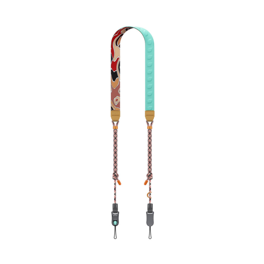 Flat lay view of a dual camera strap with red patterned fabric on left side, turquoise padding on right side, and rope connectors with metal hardware at bottom.