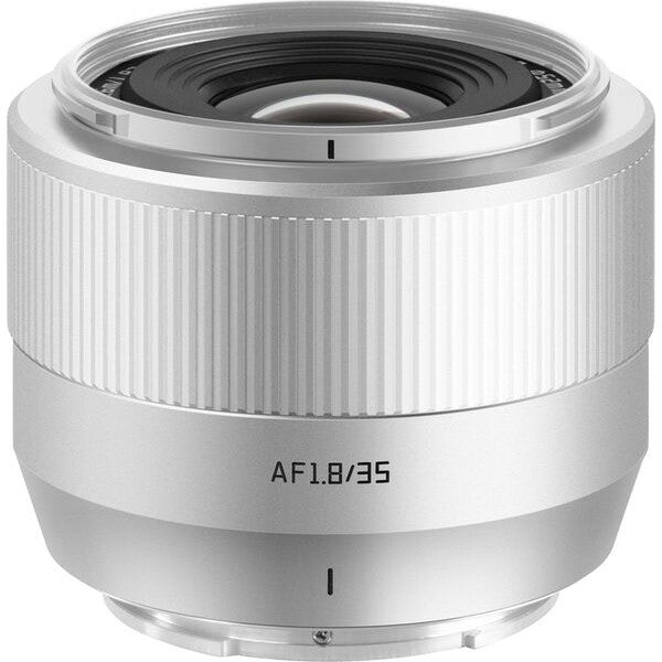 Silver prime lens shown from front angle, displaying focus ring, AF1.8/35 marking, and lens elements visible through opening.