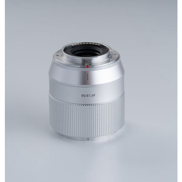 Silver TTArtisan 56mm f/1.8 lens for Fujifilm X mount, shown from front angle against neutral gray background, displaying barrel and focusing ring details.