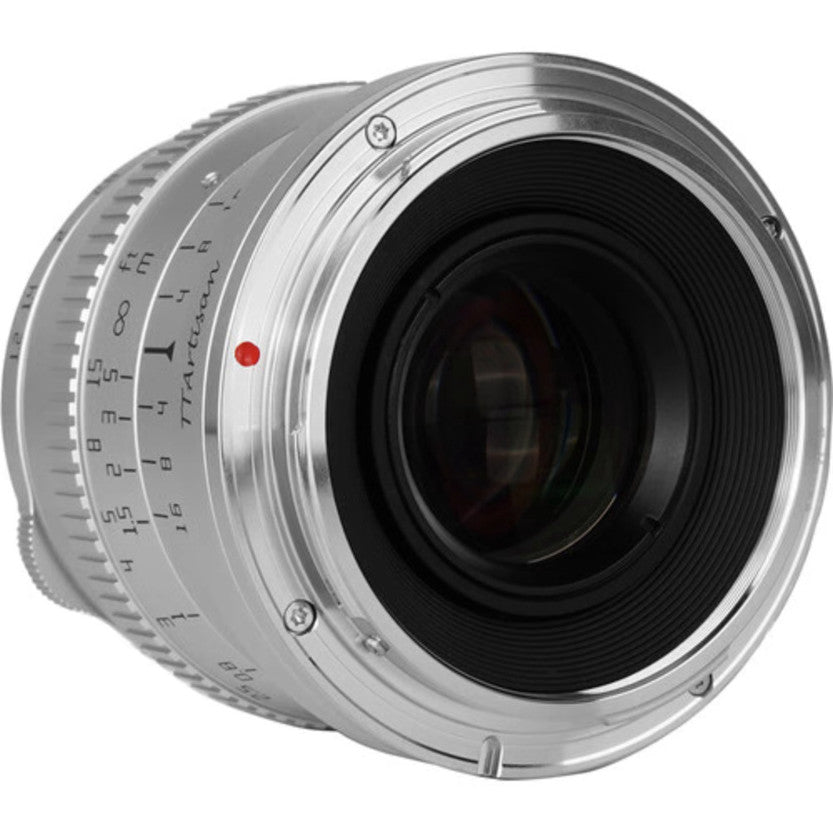 Side angle view of silver TTArtisan 50mm f/1.2 lens showing barrel with focus ring, aperture markings, and black glass elements visible through rear opening.