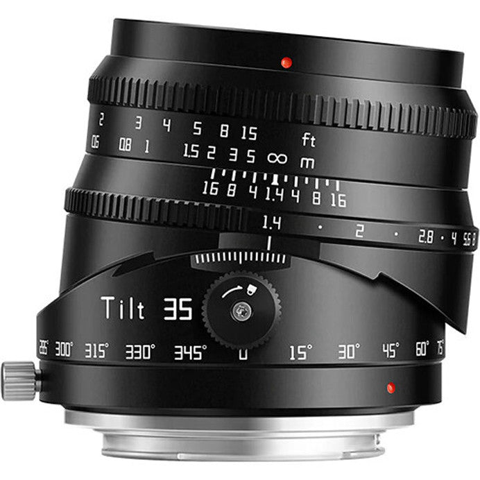 Black tilt lens photographed from front-left angle against white background, showing focus ring, aperture markings, and tilt adjustment dial with red indicator dots.