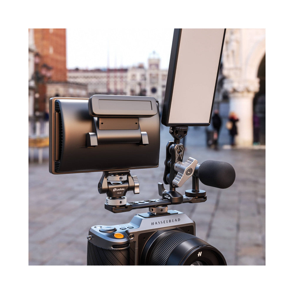 Leofoto top handle mounted on Hasselblad camera with phone holder and microphone attached, shown in use outdoors in urban setting.