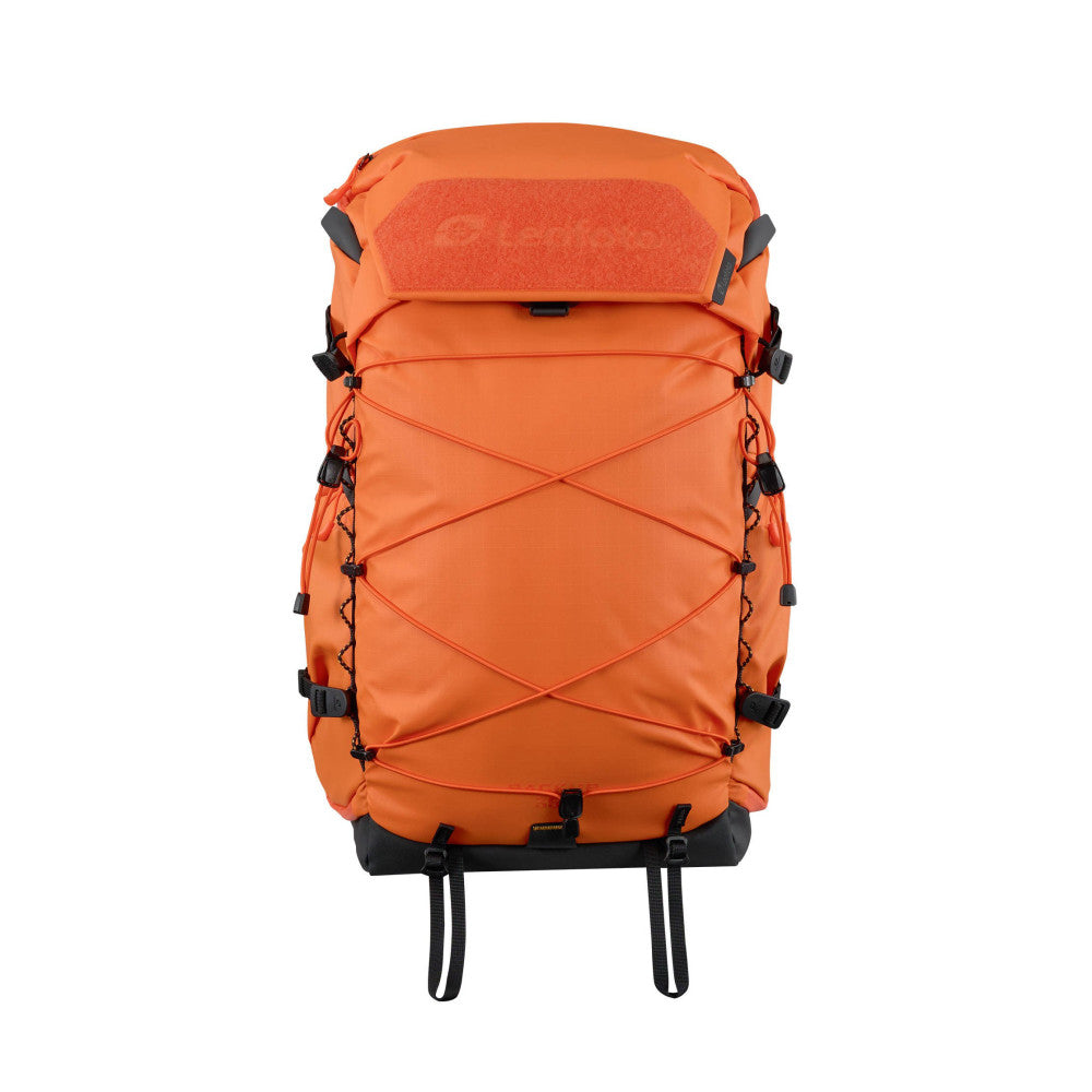 Front view of an orange camera backpack with black accents, X-shaped compression straps, and padded shoulder harness against white background.