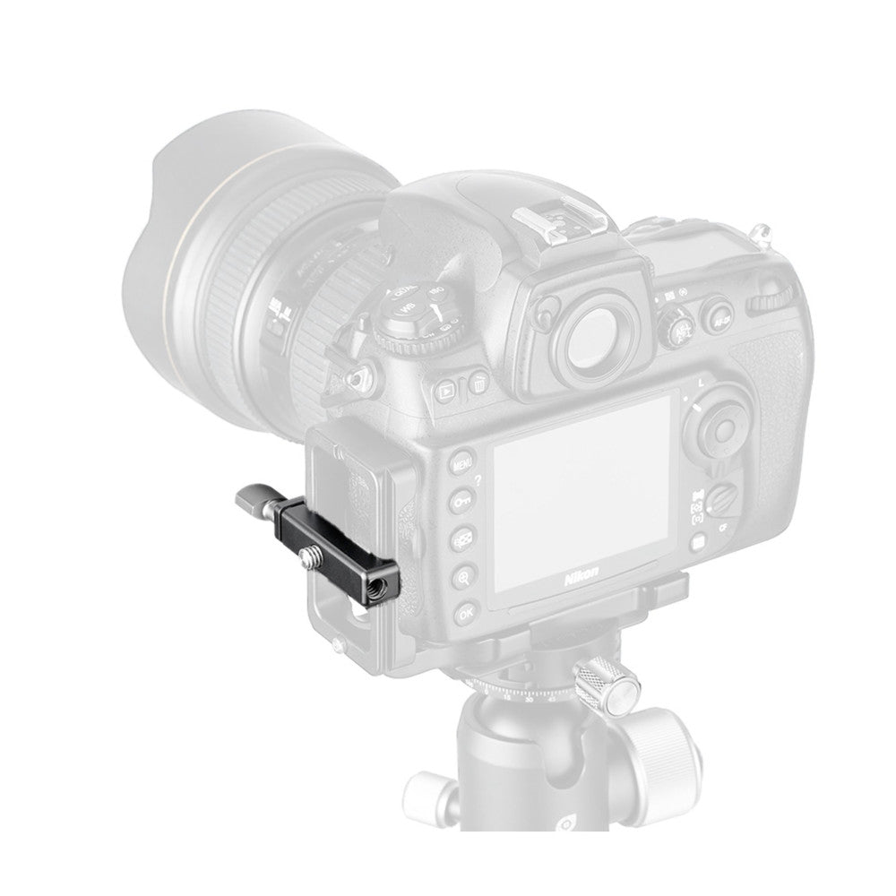 Small black Arca Swiss clamp mounted on side of DSLR camera body, shown in product demonstration photo.