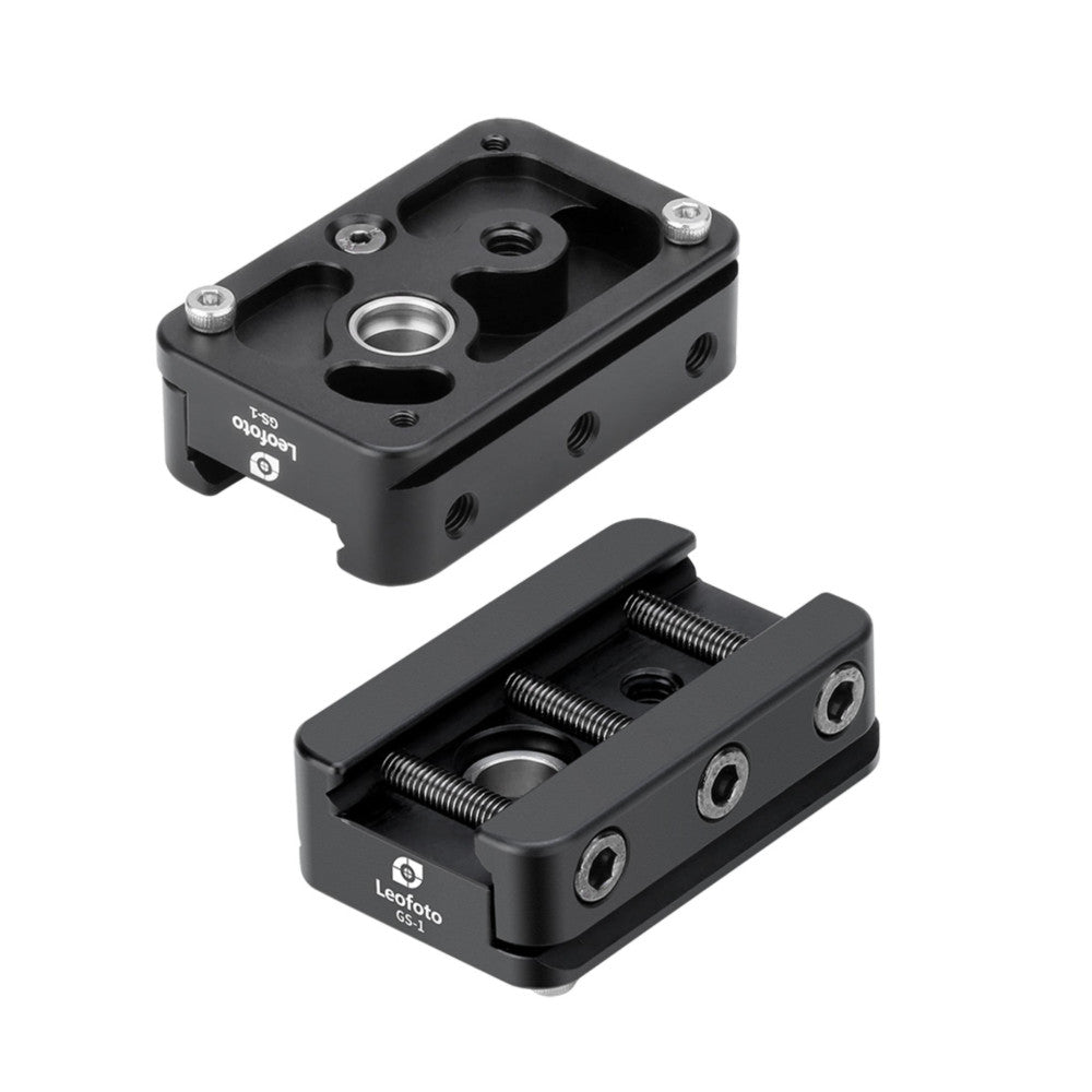 Two black metal adapter components shown from above: top unit with mounting holes and circular opening, bottom unit with spring-loaded clamp mechanism.