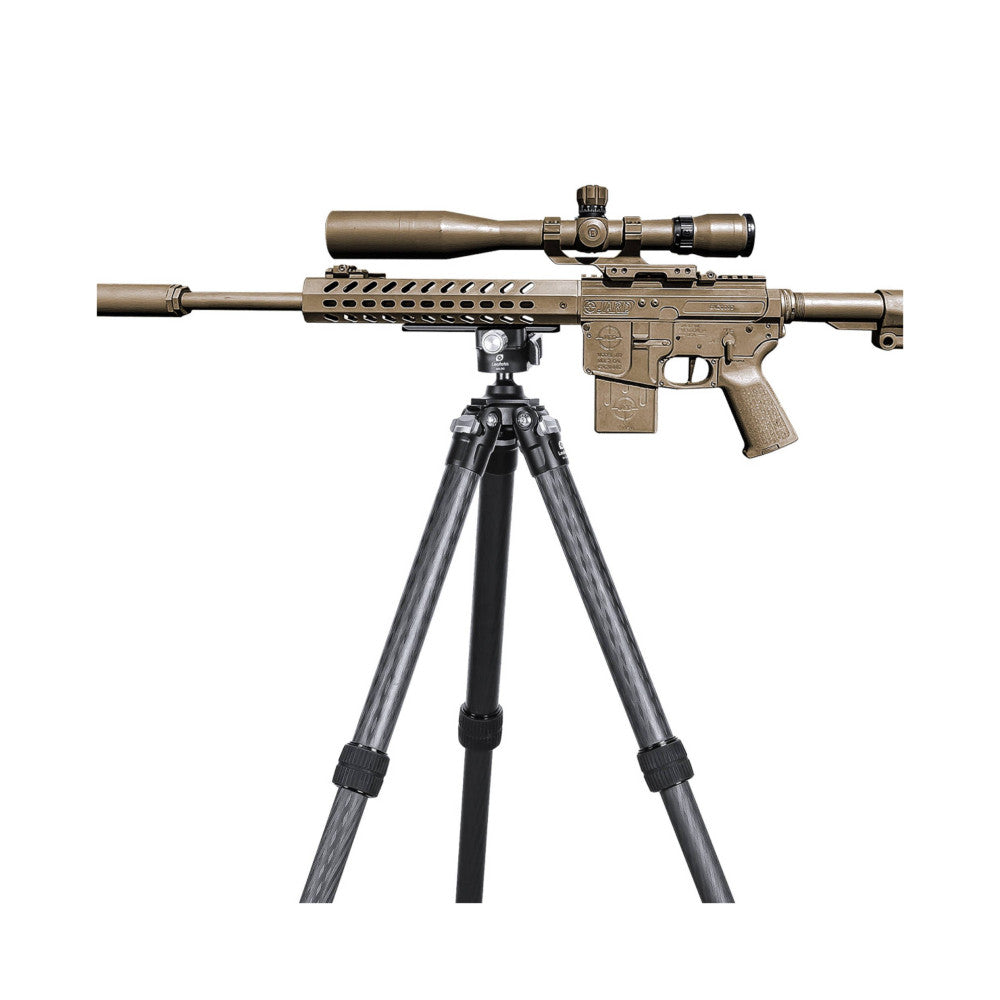 Tan AR-15 rifle with mounted scope on tripod, side view showing rifle mounted on Leofoto quick release plate and tripod legs.