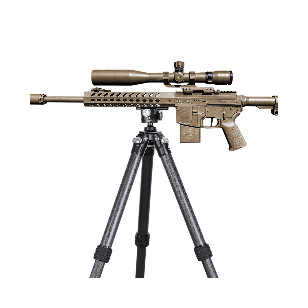 Tan AR-15 rifle with scoped mounted on gray tripod with black quick-release plate, shown from side angle against white background.